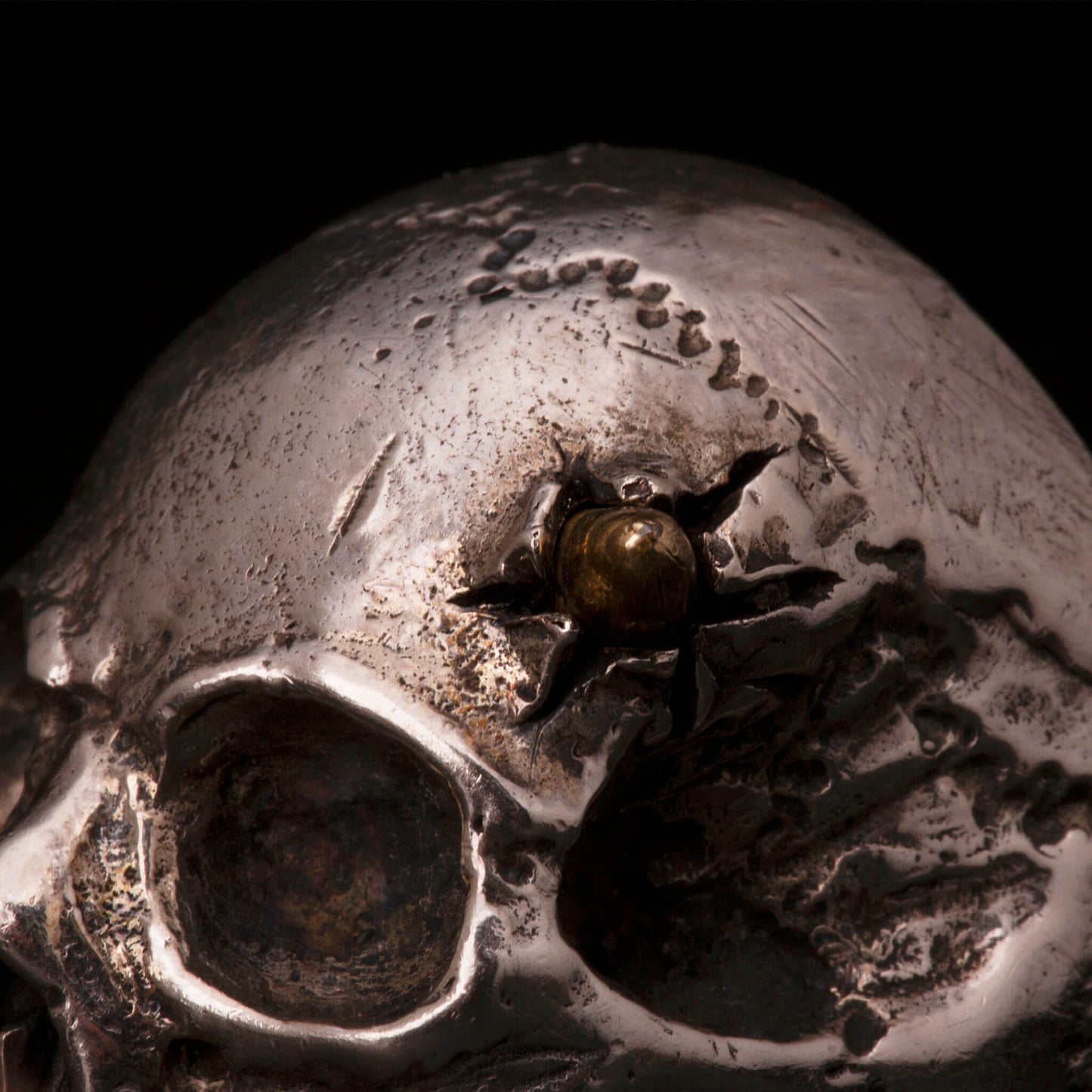 Anello in argento925 con teschio anatomico senza mandibola. Dettaglio con pallottola in ottone e foro di entrata.