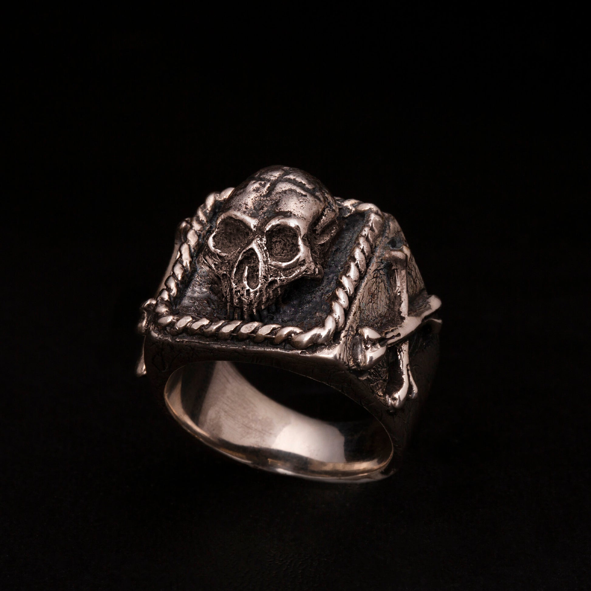 Anello chevalier in argento 925 con teschio tridimensionale e ossa incrociate sui gambi laterali.