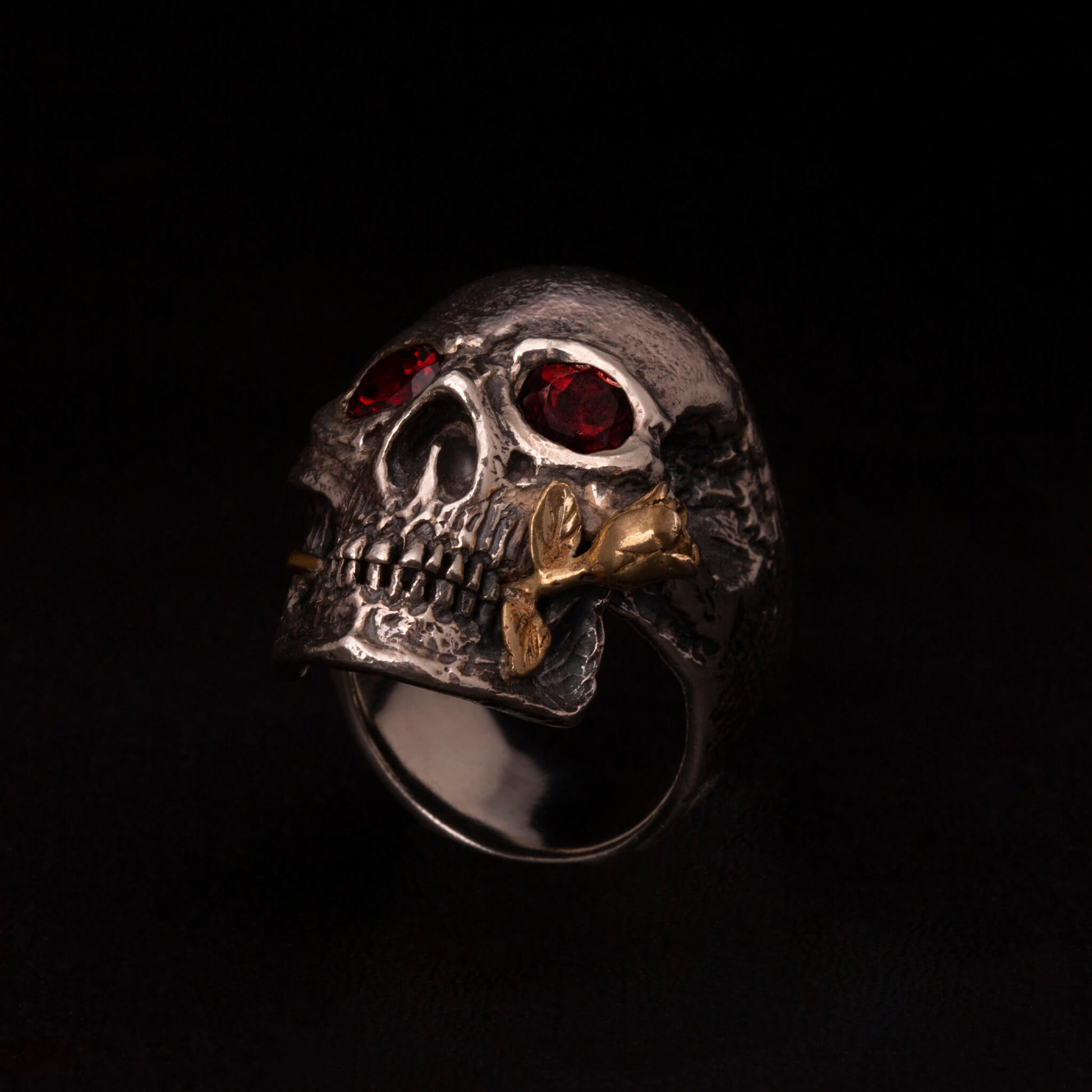 Anello in argento925 con teschio anatomico, granati incastonati nelle orbite una rosa tra i denti in ottone.