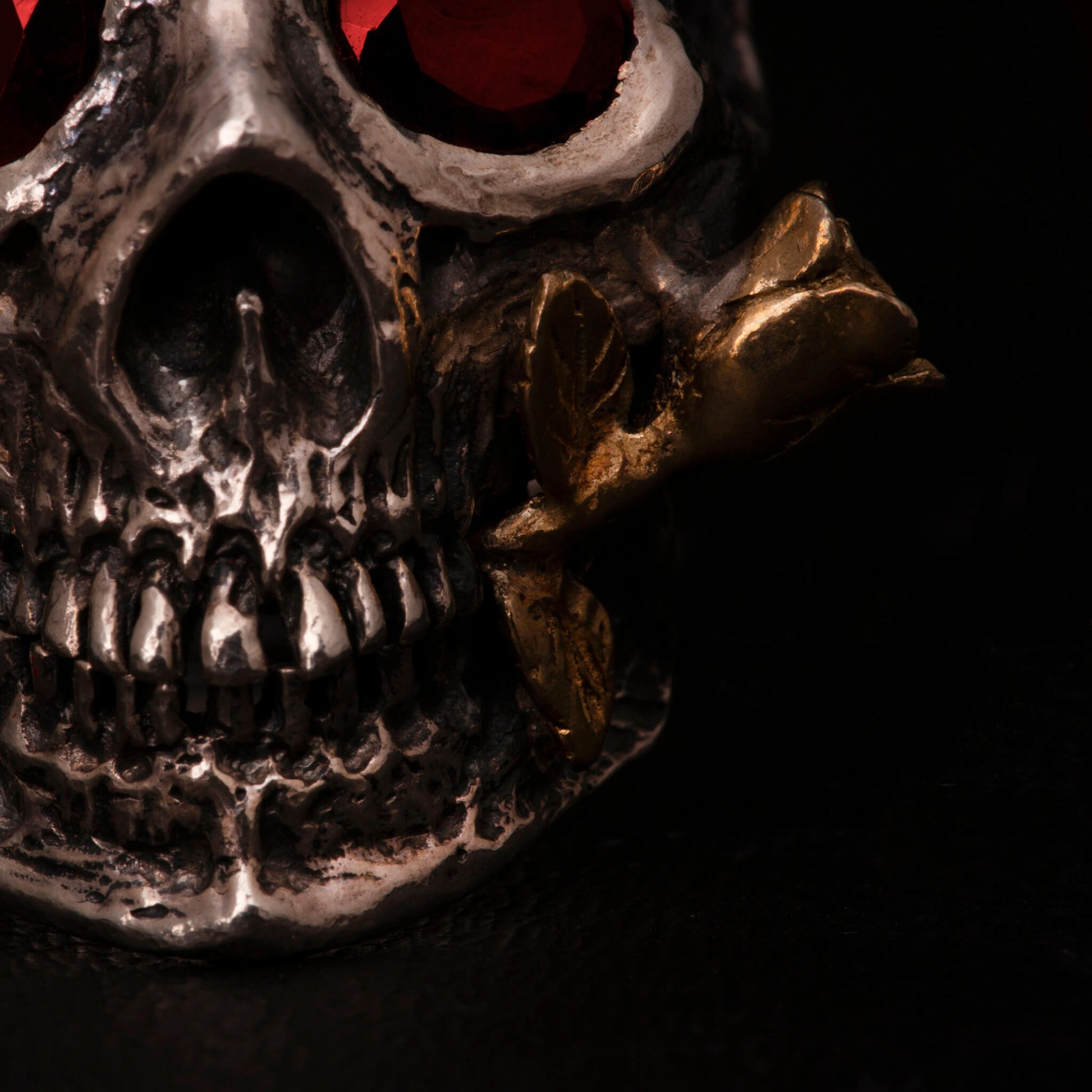 Anello in argento925 con teschio anatomico, granati incastonati nelle orbite una rosa tra i denti in ottone.