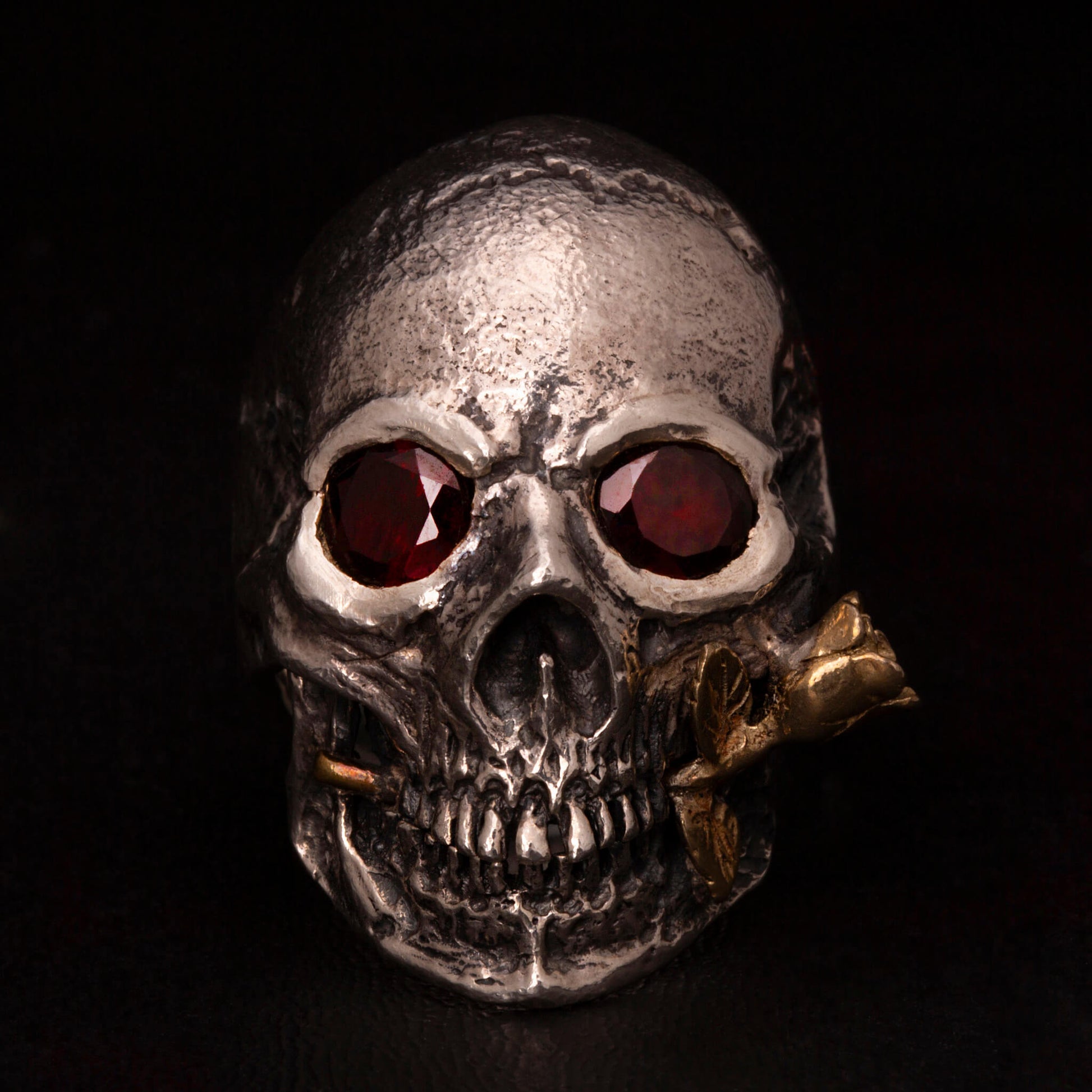 Anello in argento925 con teschio anatomico, granati incastonati nelle orbite una rosa tra i denti in ottone.