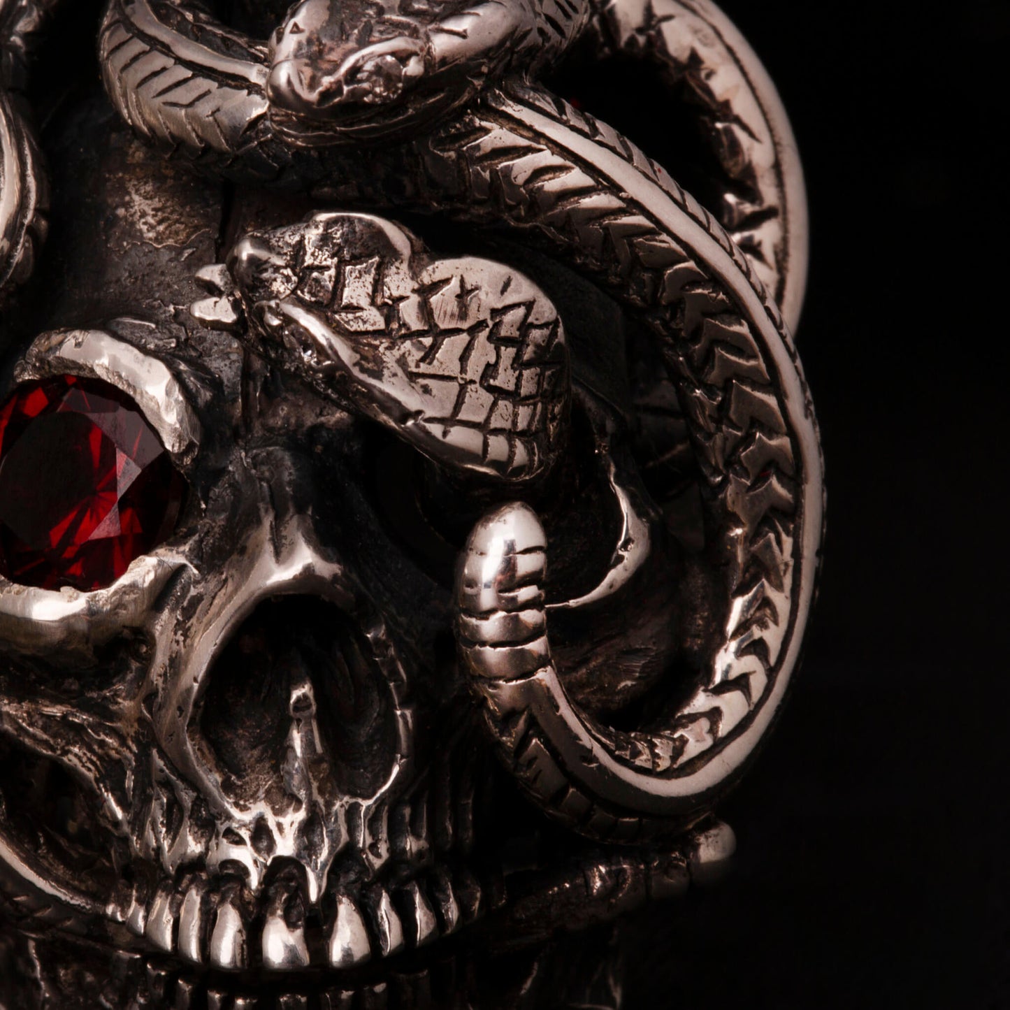 Anello in argento 925 con teschio anatomico e due serpenti avvolti. Impreziosito con diamanti naturali e granato.