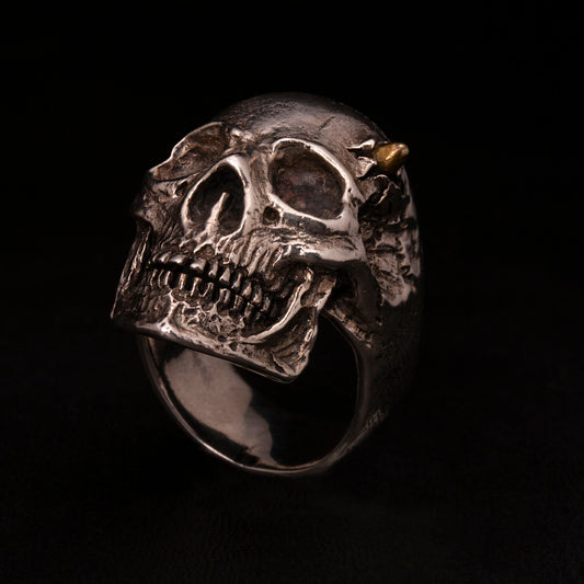Anello in argento925 con teschio anatomico e pallottola in ottone con dettaglio del foro di entrata sul cranio.