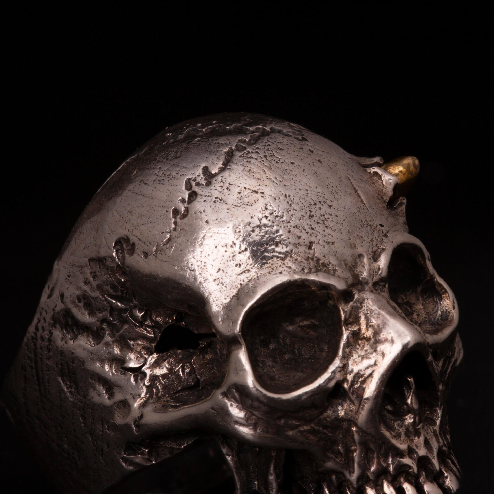 Anello in argento925 con teschio anatomico senza mandibola. Dettaglio con pallottola in ottone e foro di entrata.
