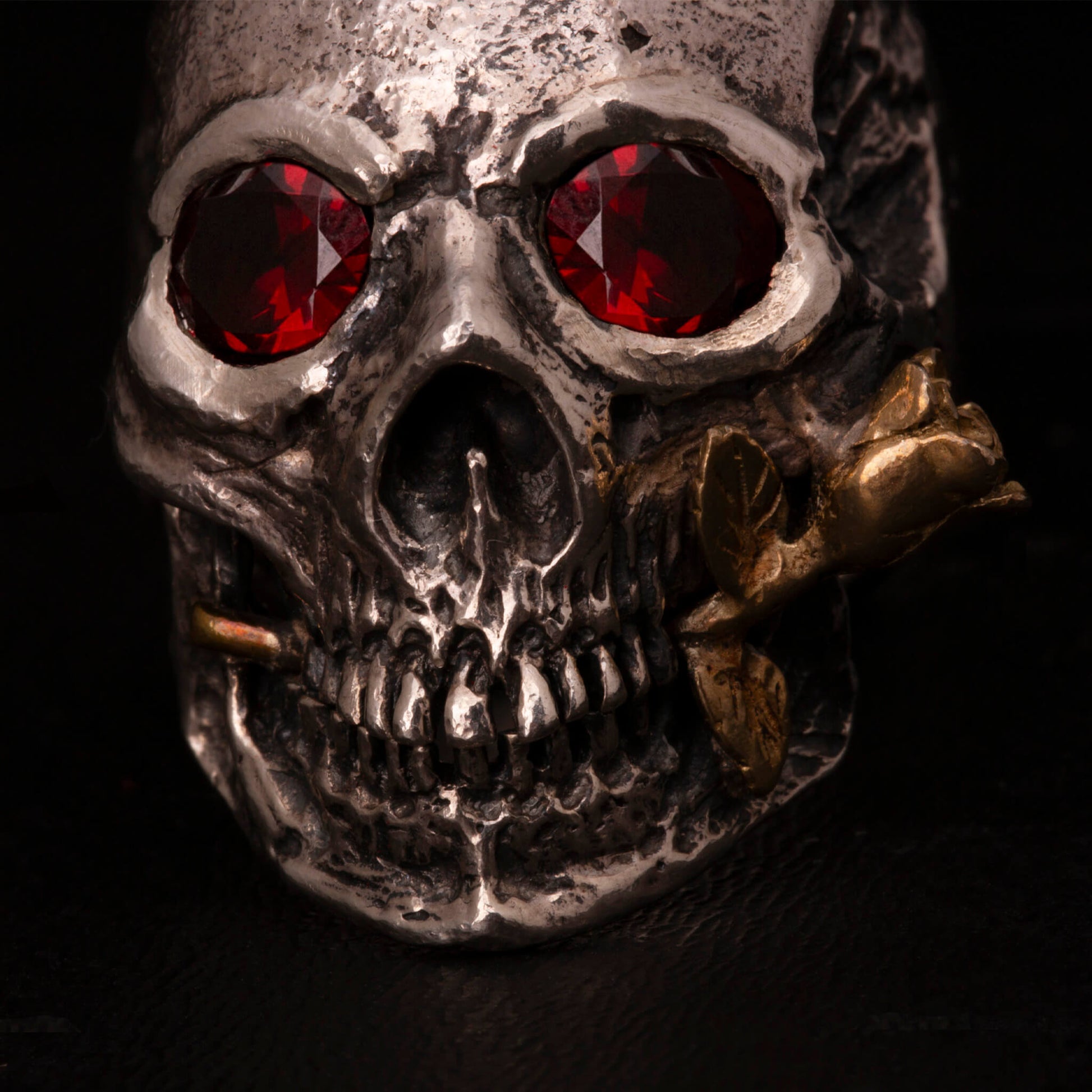 Anello in argento925 con teschio anatomico, granati incastonati nelle orbite una rosa tra i denti in ottone.