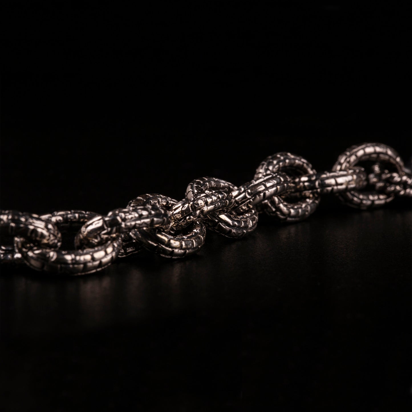 Bracciale in argento925 con maglia rolo' effetto "mattone" e due teschi con granati incastonati nelle orbite come terminali.