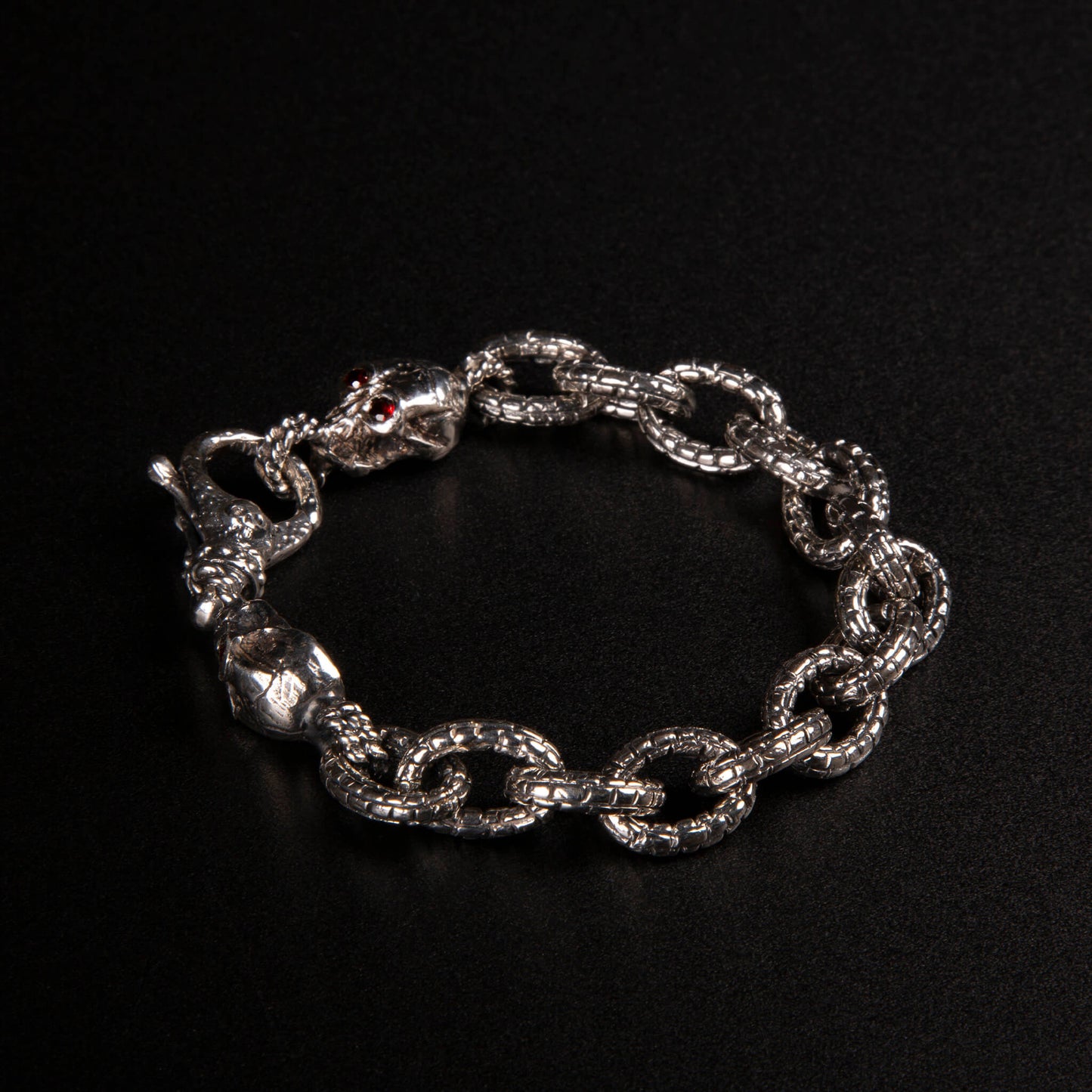 Bracciale in argento925 con maglia rolo' effetto "mattone" e due teschi con granati incastonati nelle orbite come terminali.