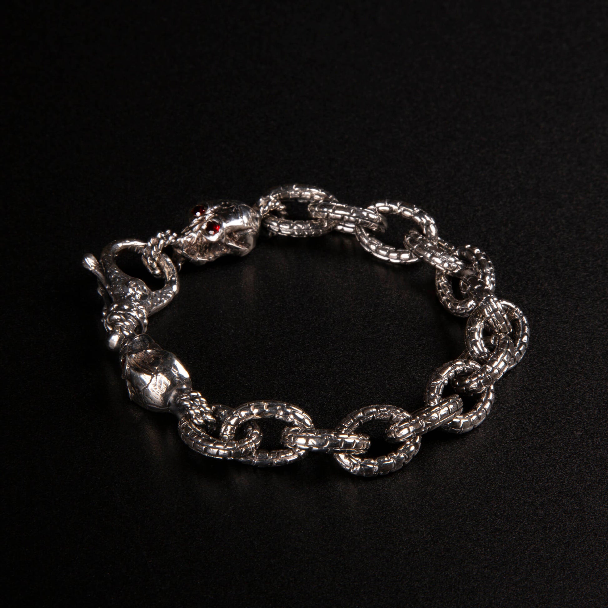 Bracciale in argento925 con maglia rolo' effetto "mattone" e due teschi con granati incastonati nelle orbite come terminali.