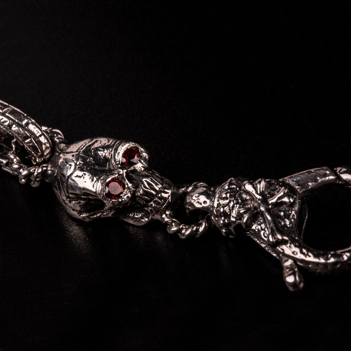 Bracciale in argento925 con maglia rolo' effetto "mattone" e due teschi con granati incastonati nelle orbite come terminali.