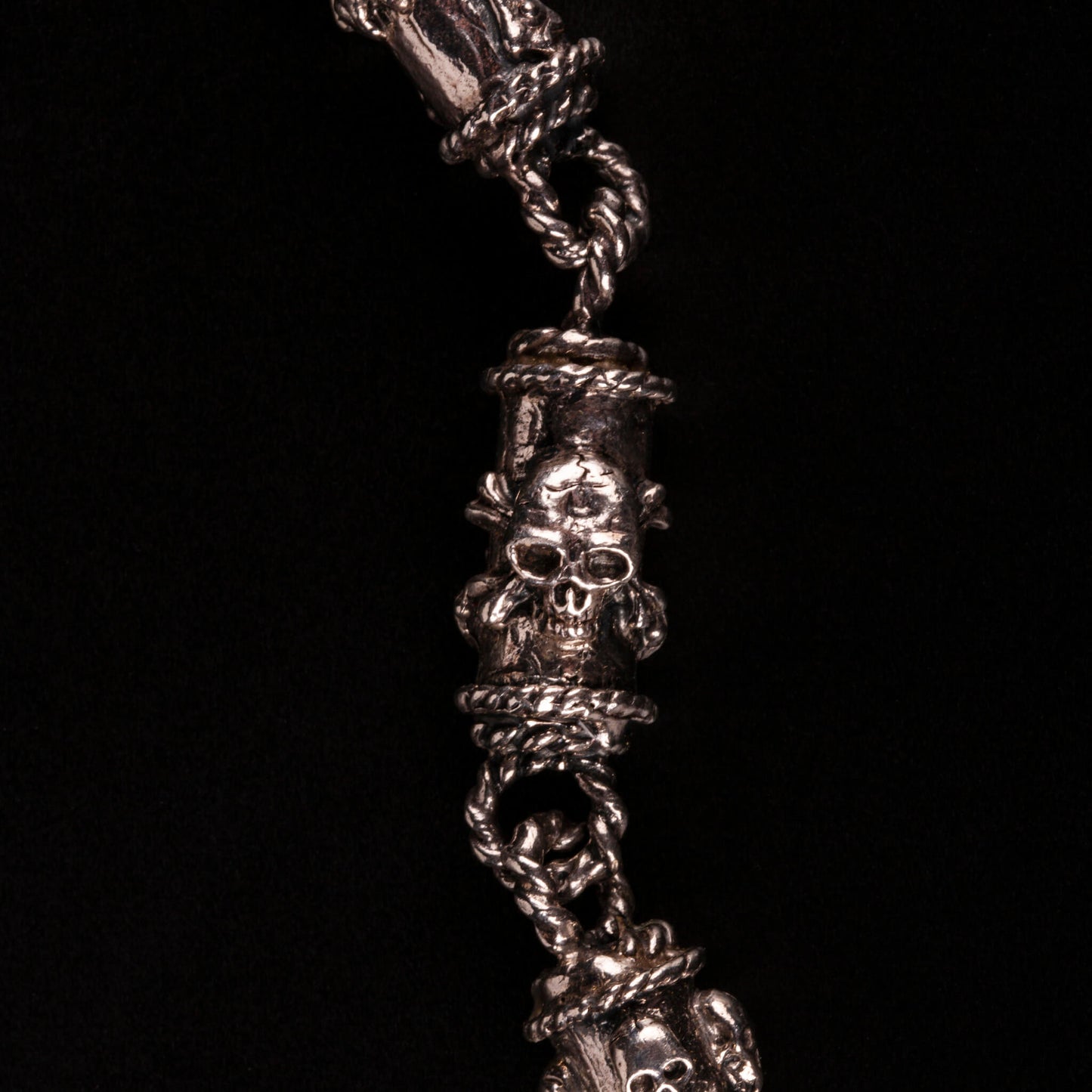 Bracciale in argento 925 con maglie tubolari finemente arricchite con teschi, cuori votivi e croci gotiche.