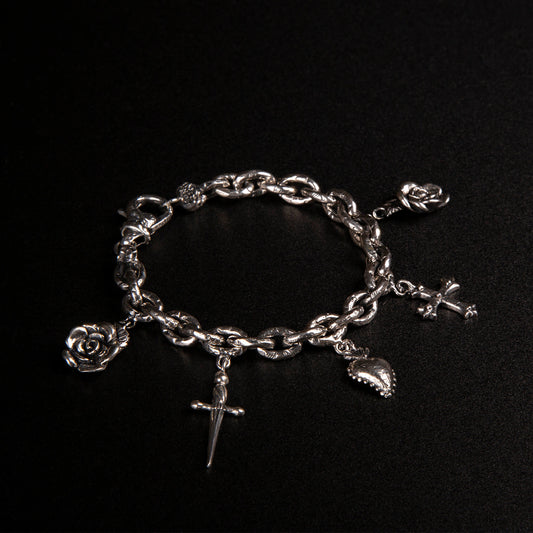 Bracciale in argento925 con maglie rolo' effetto ribattuto e charms raffiguranti rosa, pugnale, cuore votivo e croce gotica.