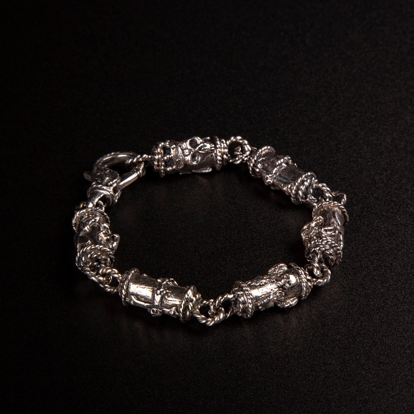 Bracciale in argento 925 con maglie tubolari finemente arricchite con teschi, cuori votivi e croci gotiche.