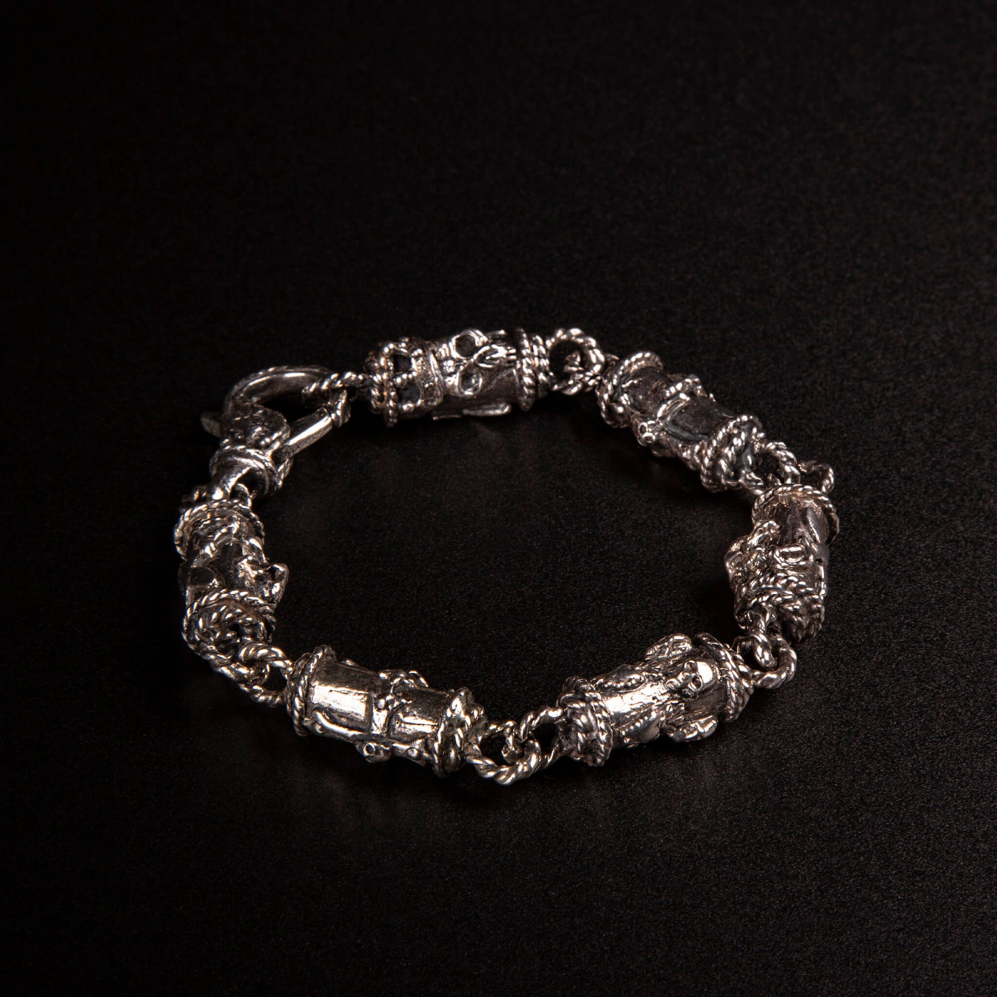 Bracciale in argento 925 con maglie tubolari finemente arricchite con teschi, cuori votivi e croci gotiche.