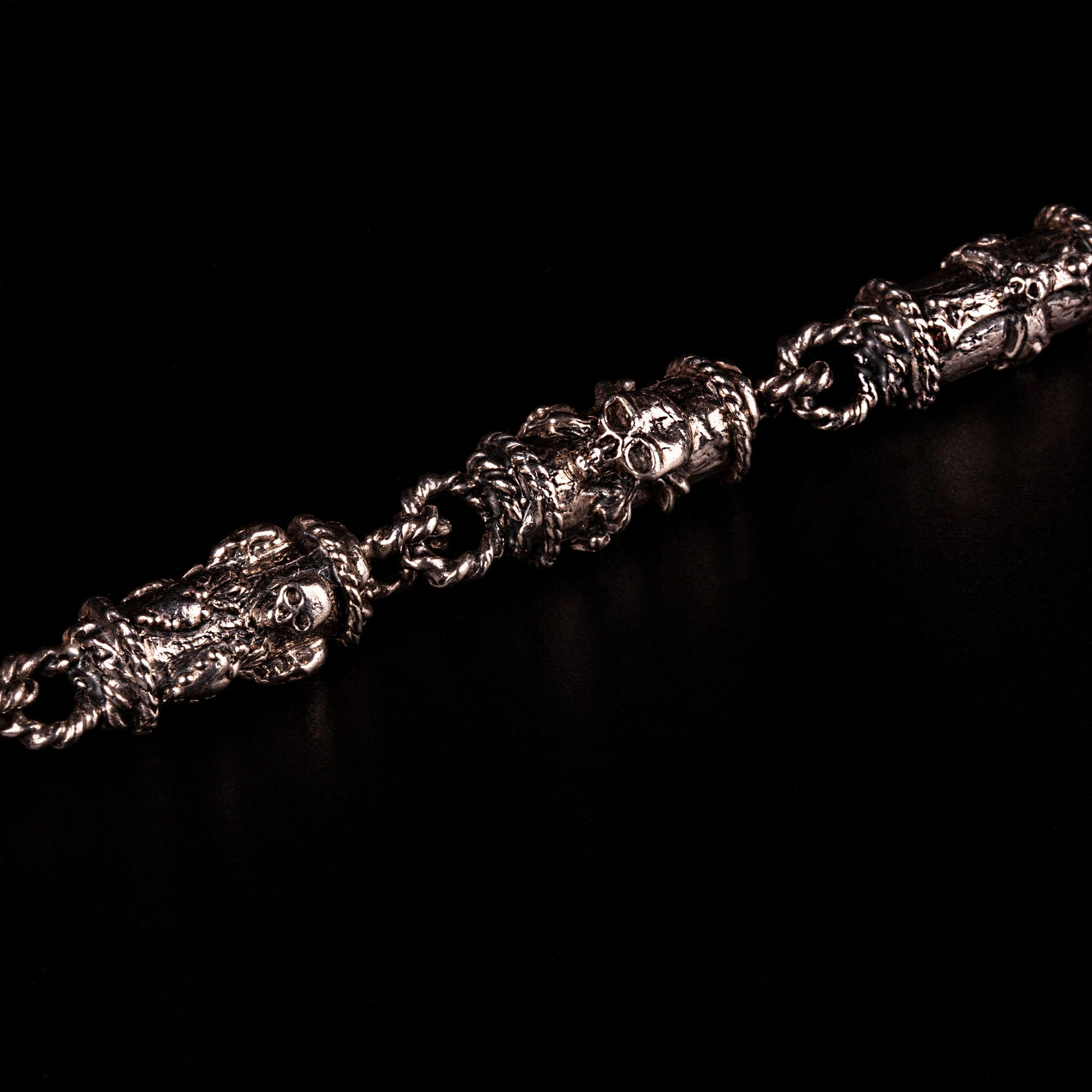 Bracciale in argento 925 con maglie tubolari finemente arricchite con teschi, cuori votivi e croci gotiche.