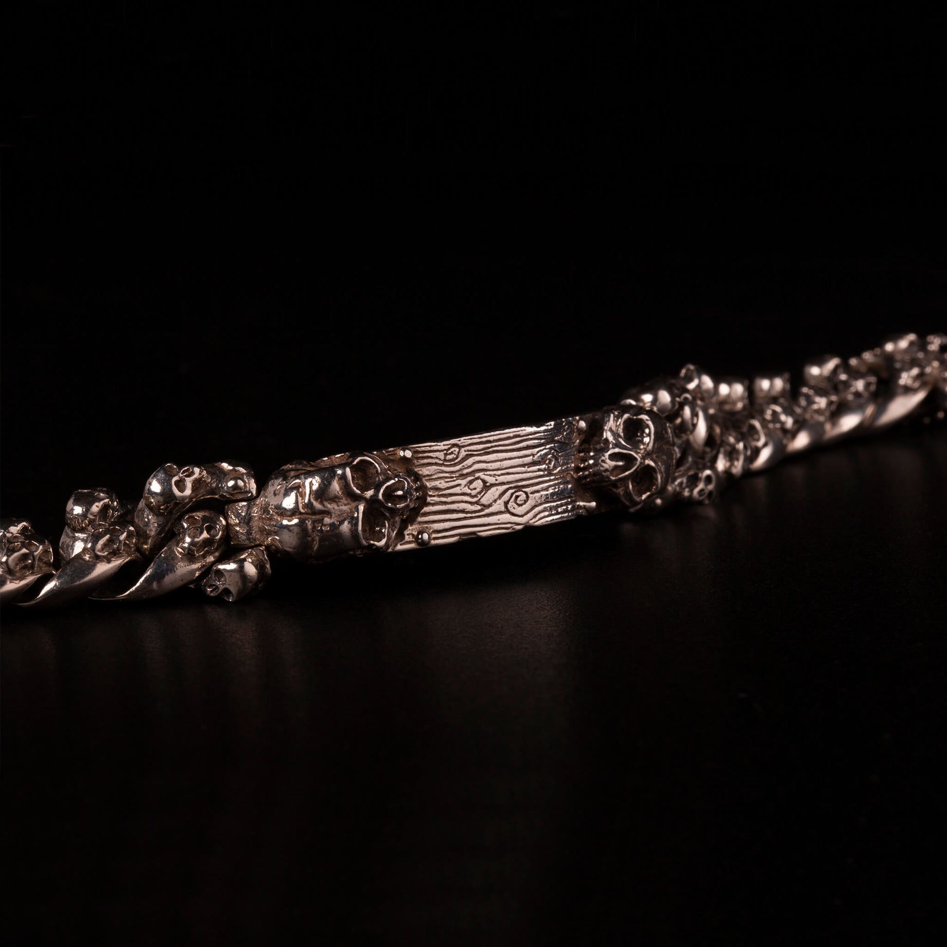 Bracciale in argento925 con maglie a grumetta sottile impreziosite da piccoli teschi e piastrina centrale effetto tavola di legno personalizzabile con due teschi alle estremita'.