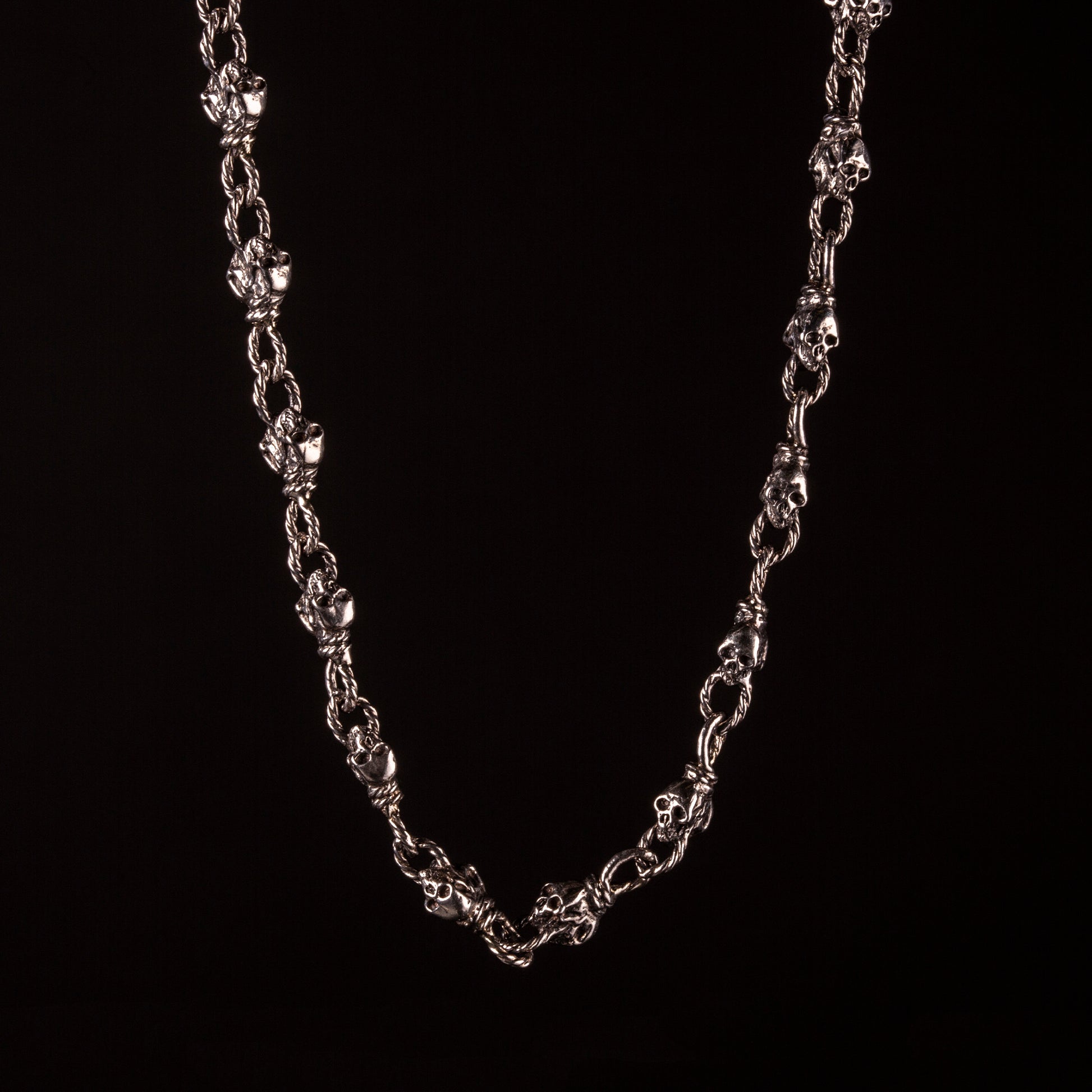 Collana con maglia effetto corda, impreziosita a piccoli teschi alternati a nodi. Creata e saldata interamente a mano.