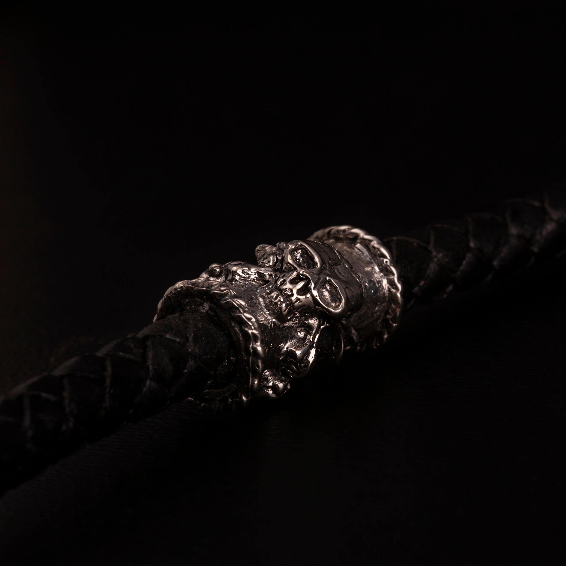 Catena portafoglio con cordino in pelle nera intrecciata ed elementi in argento925 impreziositi con teschi,croci gotiche e cuori votivi. Moschettone impreziosito con piccoli teschi e con targjetta con ala e ruota e teschio con granati.