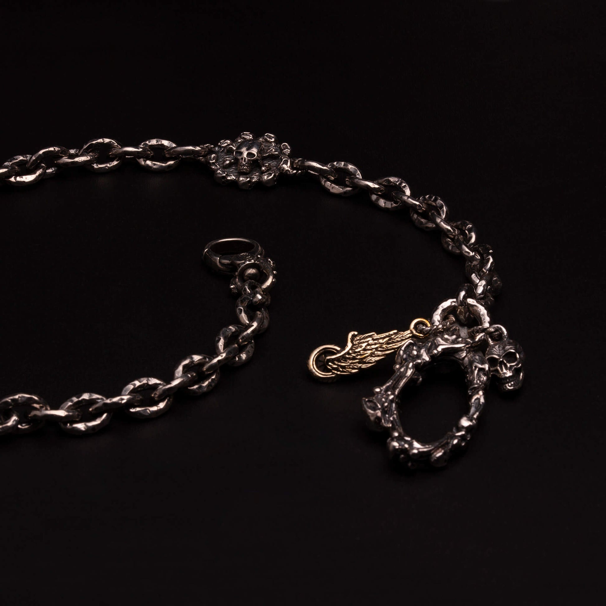 Catena portafoglio in argento925 con maglia rolo ribattuta e due medagliette con veliero e teschio pirata in rilievo. Moschettone con ossa incrociate e teschi e pendenti ruota con ala e teschio.