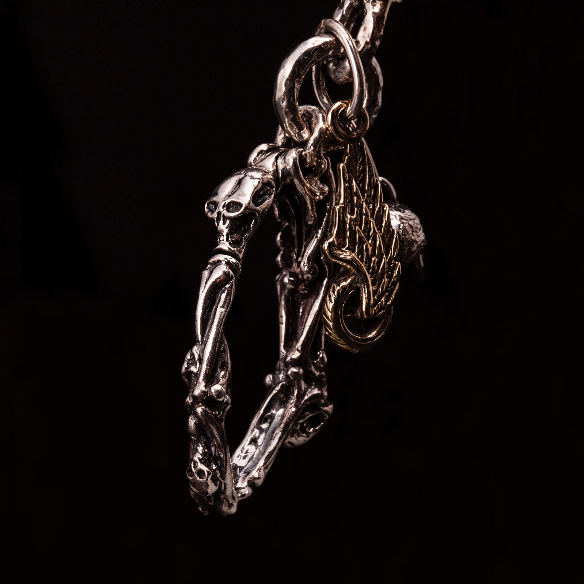 Catena portafoglio in argento925 con teschi e rose. Moschettone a molla formato da ossa incrociate e piccoli teschi.Legati come pendenti al moschettone un teschio e ruota con ala.