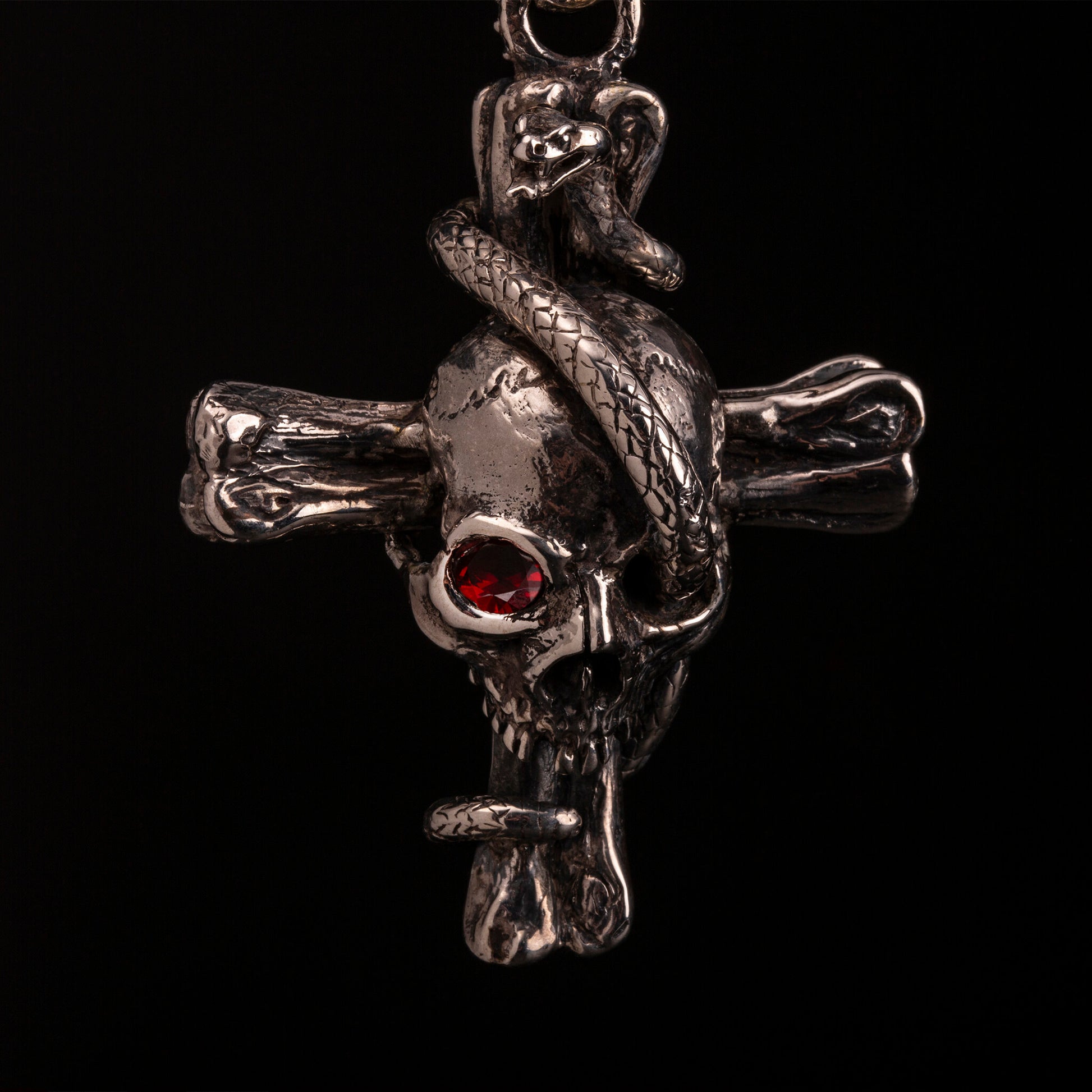 pendente in argento925 con ossa incrociate sormontate da teschio con granato e avvolto da serpente.
