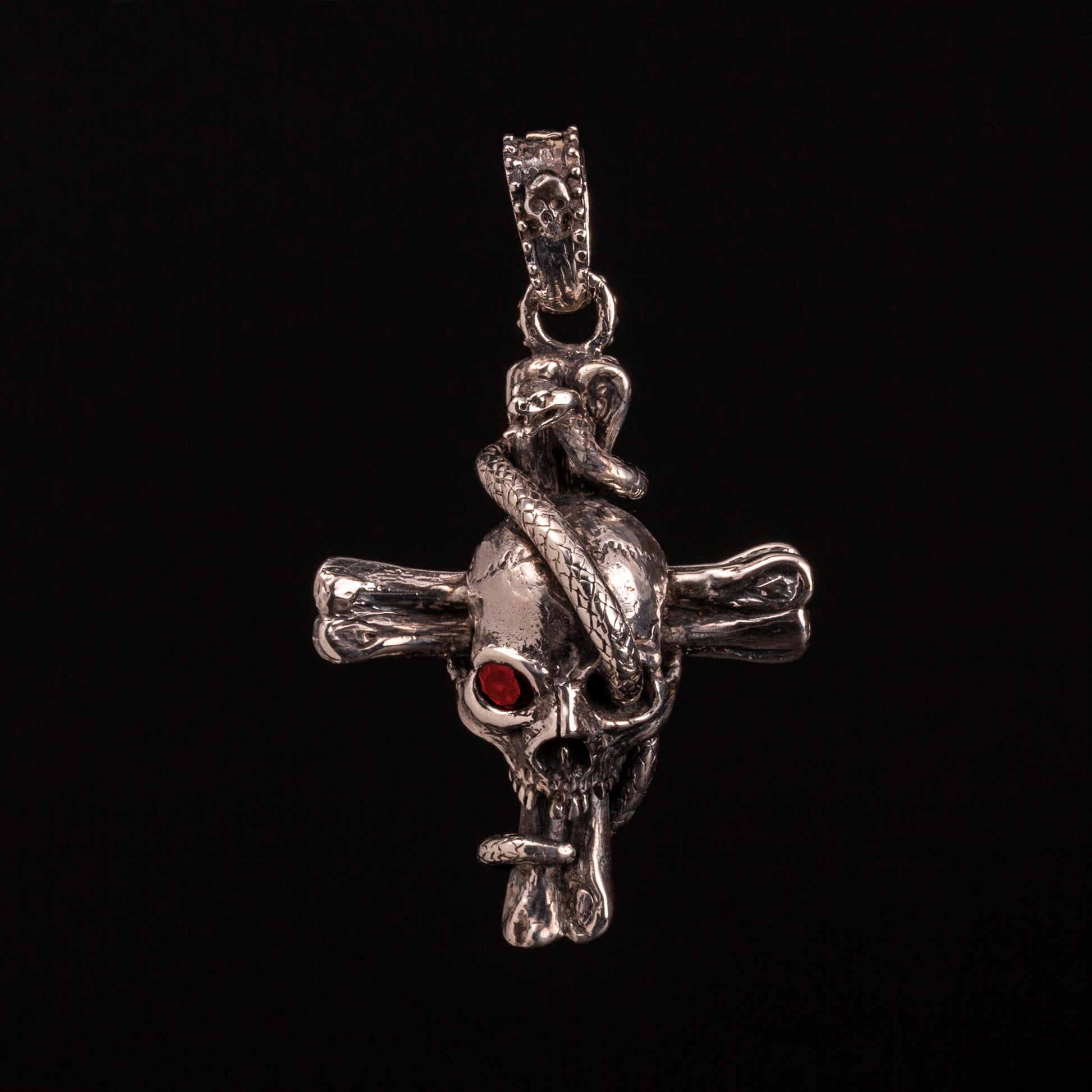 pendente in argento925 con ossa incrociate sormontate da teschio con granato e avvolto da serpente.
