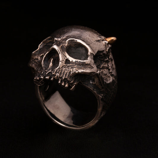 Anello in argento925 con teschio anatomico senza mandibola. Dettaglio con pallottola in ottone e foro di entrata.