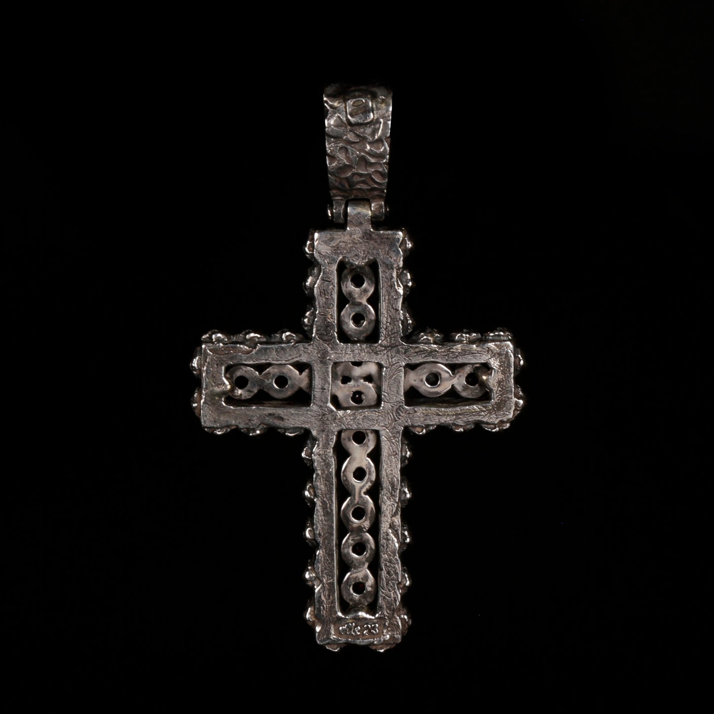 Crux Reliqvia e' un pendente a forma di croce con superficie scalfita irregolare, micro teschi saldati lungo lo spessore e incastonati granati naturali in tutta lunghezza e largezza.